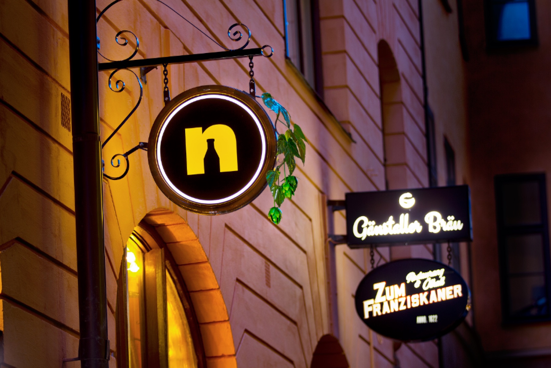 Skyltarna Nynäshamns Ångbryggeri, Gänstaller Bräu och Zum Franziskaner lyser över entrén om kvällen