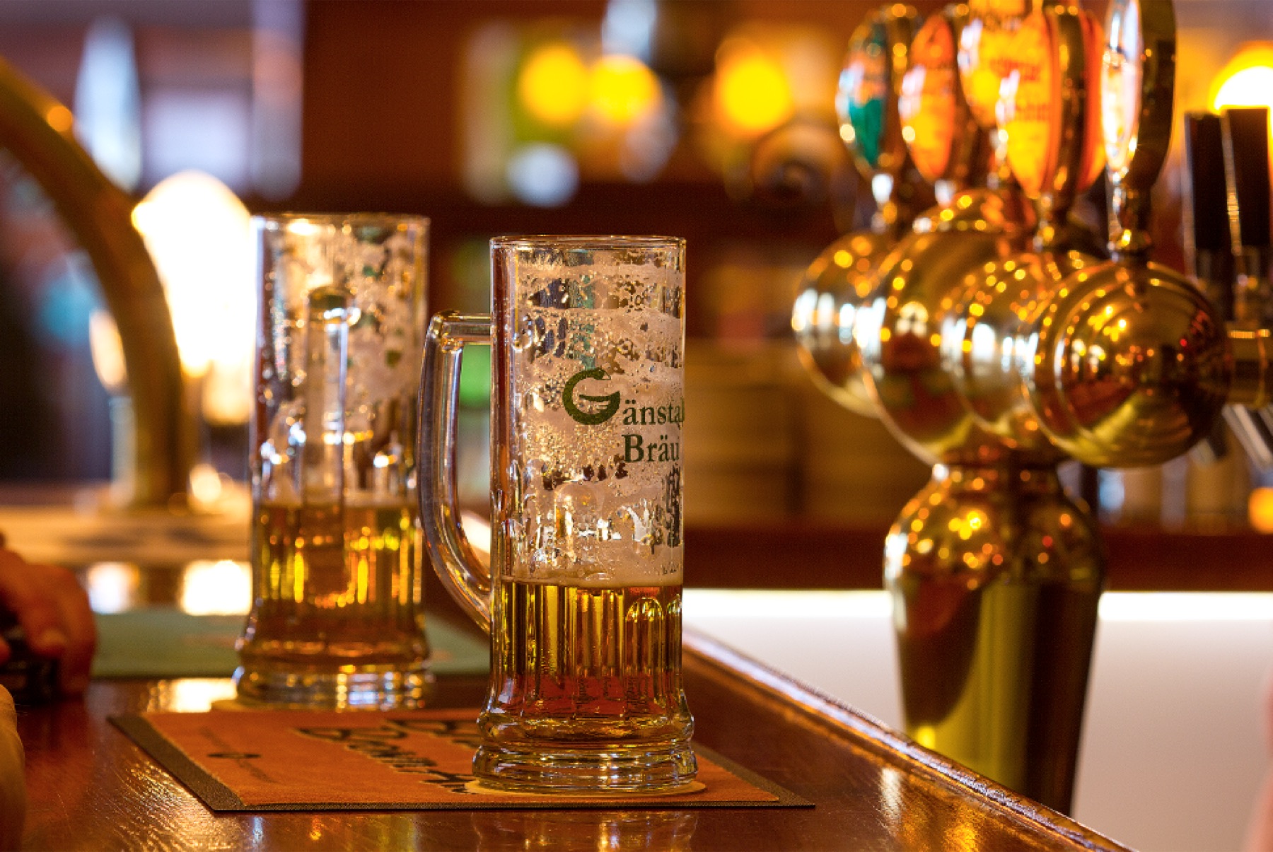 Två sejdlar Gänstaller Bräu på bardisken intill de blanka mässingskranarna